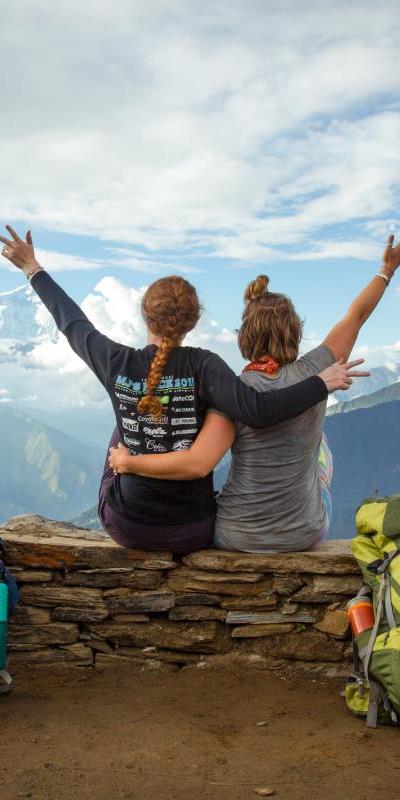 2 girls sitting together looking over the Himalayas during yoga teacher training Nepal