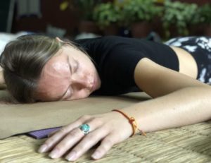 A woman sleeping in belly on Yoga mat in Yoga Nidra Training