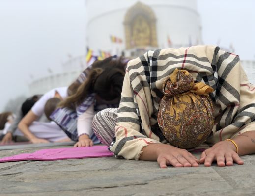 women doing child pose in front of Peace pagoda during her 300 hour Yoga training in Nepal