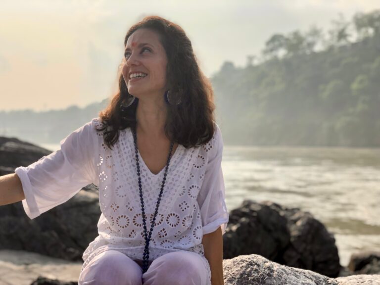 a woman smiling after silent meditation at river ganga in Rishikesh
