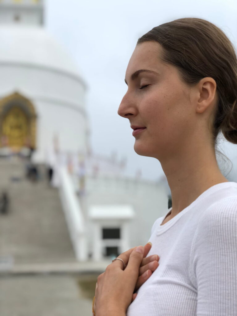 A woman with hands on her chest during meditation course